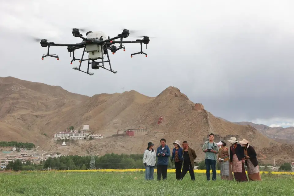 A technical professional and a local skillful farmer teach villagers how to use unmanned aerial vehicles for crop protection in a village in Qonggyai county, southwest China’s Tibet autonomous region, June 17, 2021. (Photo by Wang Hu/People’s Daily Online)