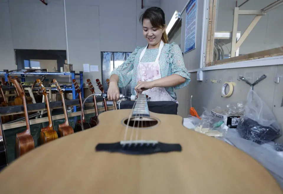 A woman makes guitar at a factory of guitar-making company Natasha in the guitar industrial park in Zheng’an county, southwest China’s Guizhou province, June 26, 2021. (Photo by Zhao Yongzhang/People’s Daily Online)