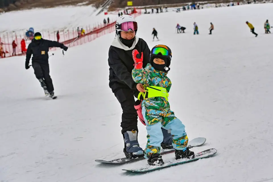 A child learns to ski with the help of his mother at a ski resort in Qingzhou city, east China’s Shandong province, Jan. 5, 2022. (Photo by Wang Jilin/People’s Daily Online)