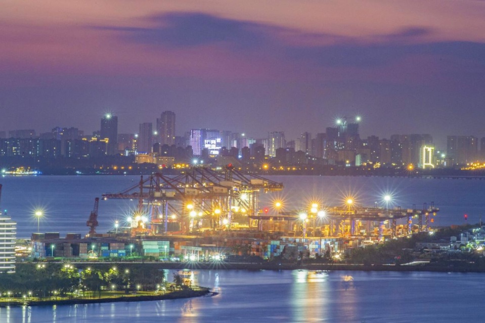 Containers are loaded and unloaded at a well-lit container terminal of Haikou port, south China’s Hainan province, Oct. 20, 2021. (Photo by Wang Chenglong/People’s Daily Online)