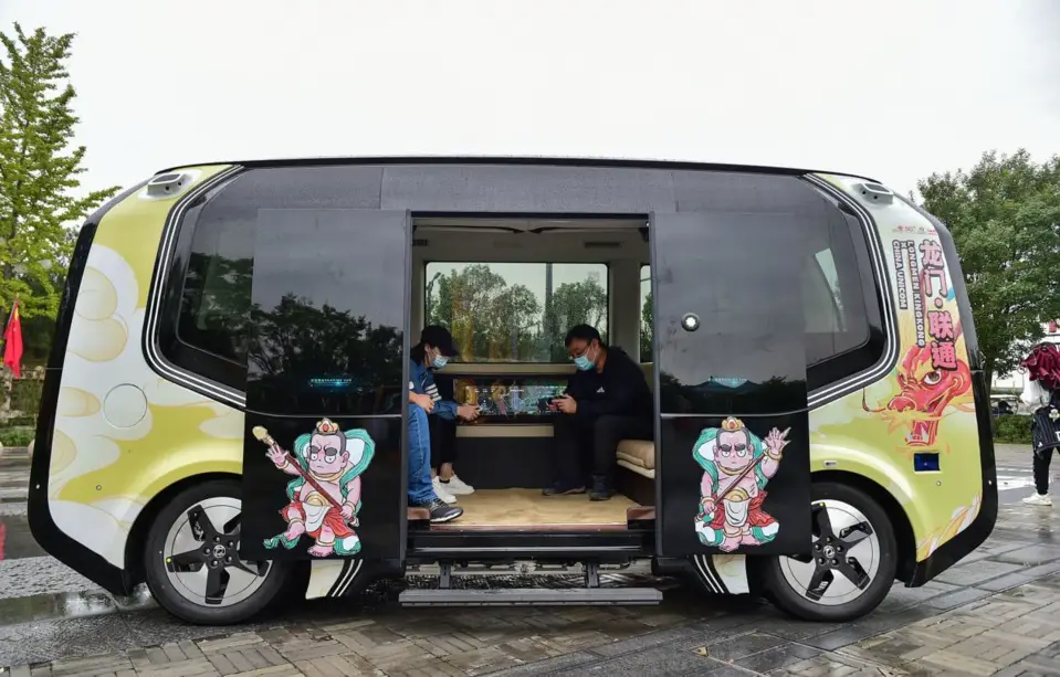 Visitors sit in a 5G-driven autonomous vehicle at the tourist service area of the Longmen Grottoes, a world cultural heritage site in Luoyang, central China’s Henan province, Oct. 4, 2021. (Photo by Huang Zhengwei/People’s Daily Online)