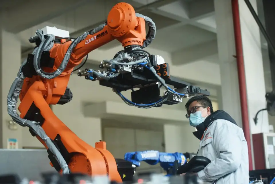 An engineer debugs an industrial robot that's about to be delivered at a workshop in a robotics industrial park in Xiaoshan, Hangzhou, east China's Zhejiang province, Jan. 17. (Photo by Long Wei/People's Daily)