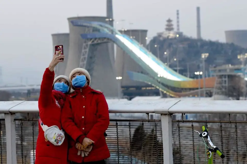 Citizens take selfies near Big Air Shougang, a venue for Beijing 2022 Winter Olympic Games. (Photo by Li Wenming/People’s Daily Online)