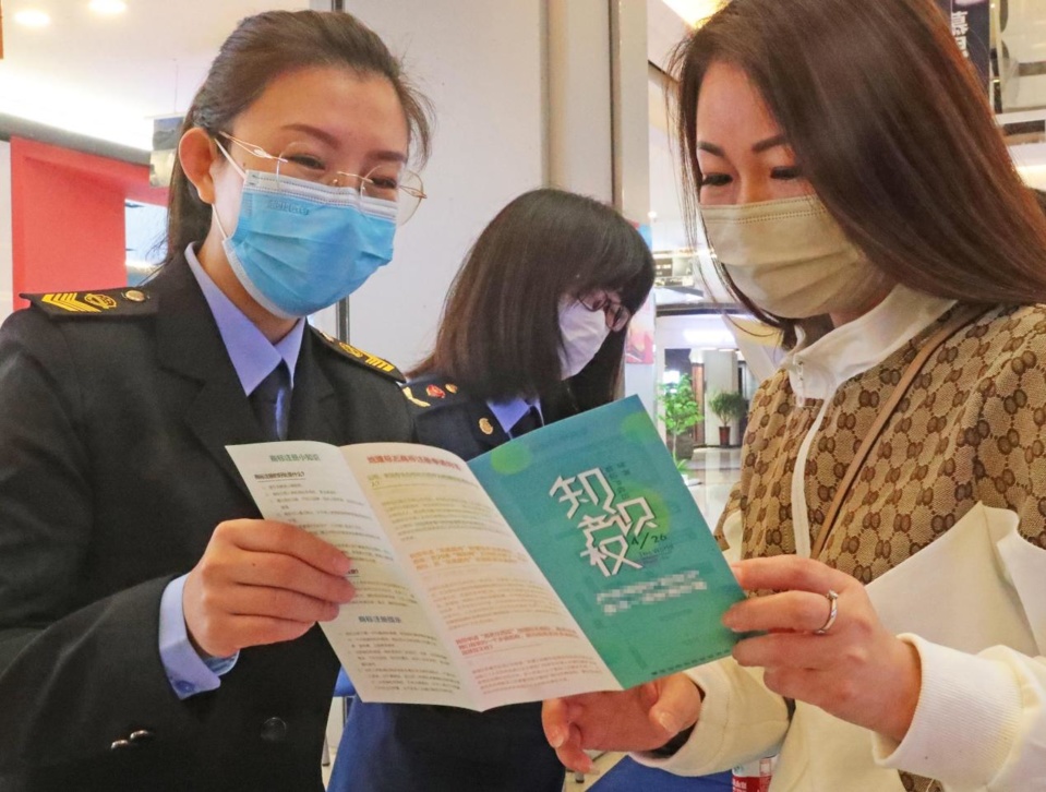 Officials with the administration for market regulation in Haigang district, Qinhuangdao, north China's Hebei province introduce intellectual property rights protection to a merchant, April 20, 2022. (Photo by Cao Jianxiong/People's Daily Online)