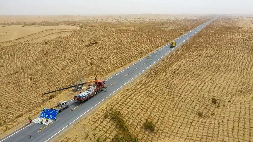 Photo taken on May 13, 2022 shows workers installing a road sign with a crane at the K039 section of the third desert highway in northwest China’s Xinjiang Uygur autonomous region. The highway linking Yuli county and Qiemo county in Bayingolin Mongolian autonomous prefecture, Xinjiang, is expected to open to traffic at the end of June. (Photo by Li Fei/People’s Daily Online)