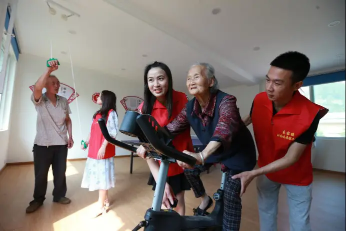 Volunteers instruct senior citizens to use fitness equipment at a day-care nursing facility in Aoling community, Gaojia township, Meishan, southwest China's Sichuan province, May 7, 2022. (Photo by Zhang Zhongping/People's Daily Online)
