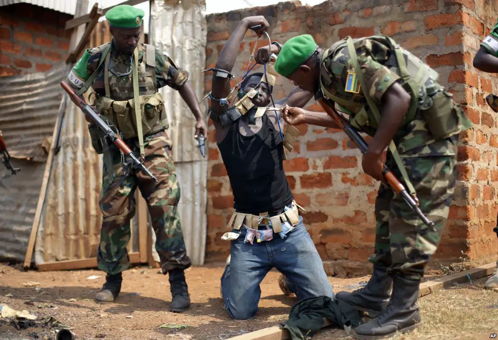 Rwandan African Union peacekeepers remove the lucky charms from a suspected Anti-Balaka Christian man who was found with a rifle and a grenade following looting in the Muslim market of the PK13 district of Bangui, Central African Republic.