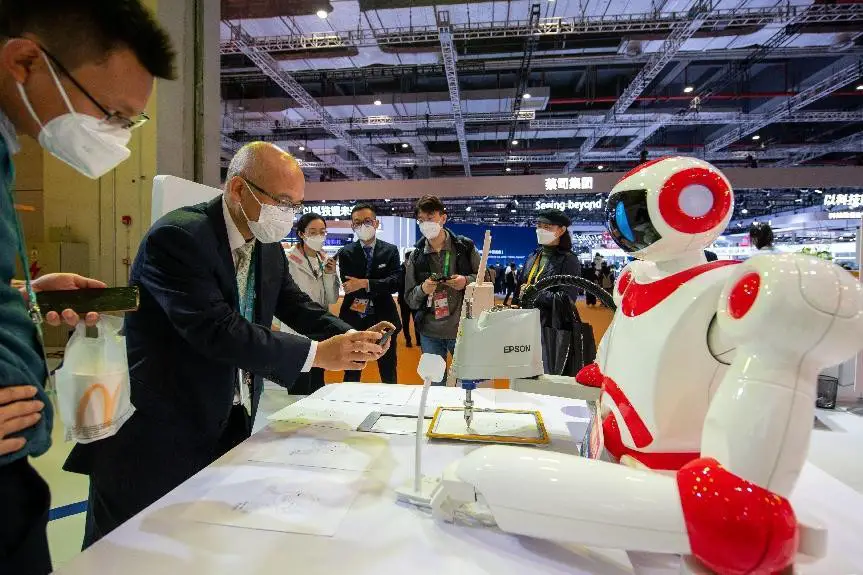 A robot developed by Japanese electronics maker Seiko Epson draws a portrait of a visitor at the fifth China International Import Expo, Nov. 5, 2022. (Photo by Weng Qiyu/People's Daily Online)