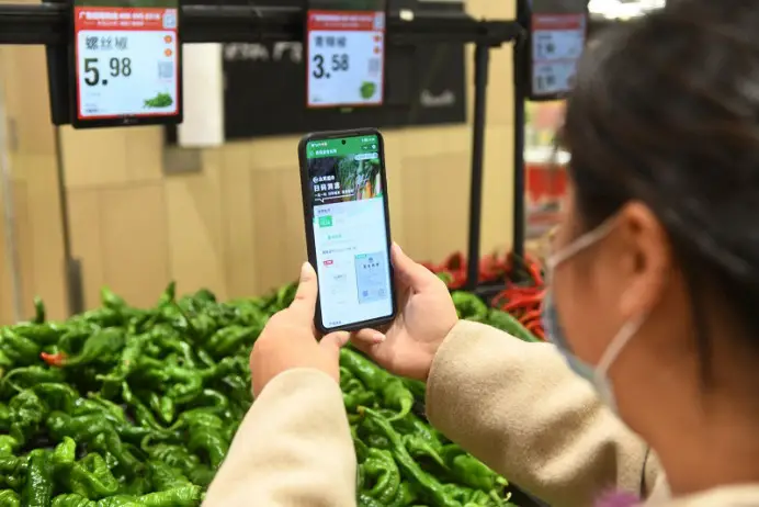 A citizen scans a QR code to obtain information about vegetables at a supermarket in Fuyang, east China's Anhui province, October 2022. (Photo by Wang Biao/People's Daily Online)