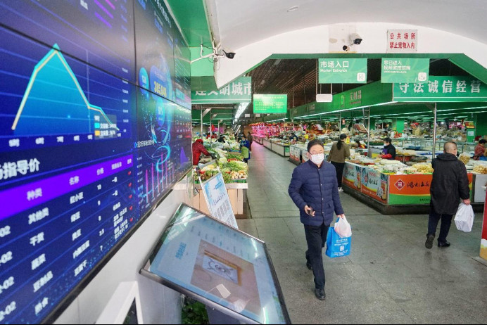 A citizen walks by a "big data" screen in a market in Jiaxing, east China's Zhejiang province. (Photo by Jin Peng/People's Daily Online)