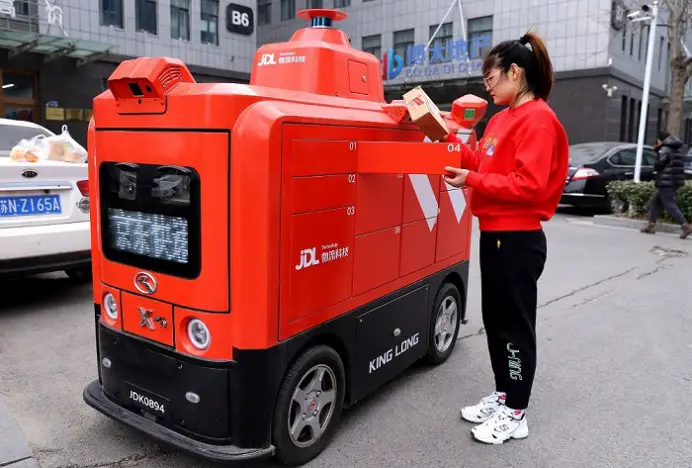 A woman fetches express delivery parcels from an intelligent delivery vehicle in a national e-commerce demonstration base in Suyu district, Suqian, east China's Jiangsu province, January 2022. (Photo by Sun Dongcheng/People's Daily Online)