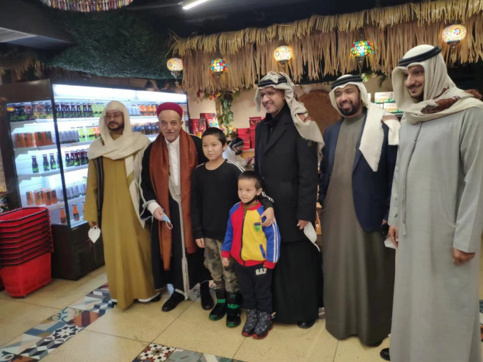 A delegation of world-renowned Islamic figures and scholars take a photo with local residents at the Xinjiang International Grand Bazaar, one of the most famous landmarks in Urumqi, capital of northwest China's Xinjiang Uygur autonomous region.