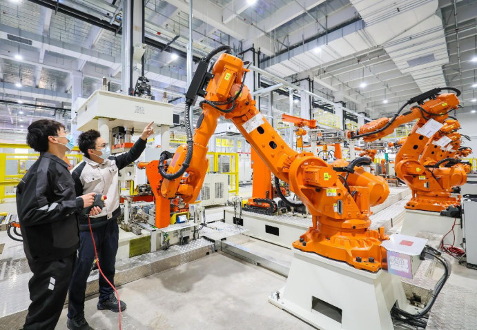 A smart washing machine factory of Chinese home appliance giant Haier is put into use in Songjiang district, Shanghai, Dec. 29, 2022. Photo shows technicians debugging robotic arms. (Photo by Cai Bin/People's Daily Online)