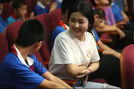 A volunteer of "Ever Shining Cinema", a public-service project aimed at interpreting movies for people with visual impairment, talks with a student from Beijing School for the Blind about the movie he just "watched". (Photo/Official website of Communication University of China)