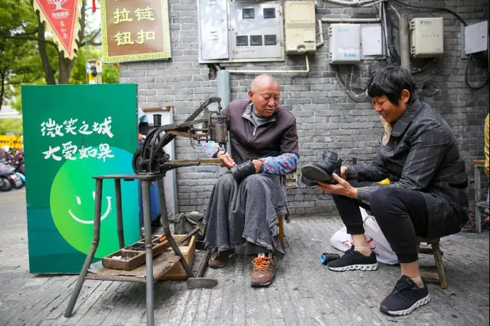 A citizen has her shoes fixed at a curbside cobbler booth in Rucheng neighborhood, Rugao, east China's Jiangsu province, May 12, 2023. (Photo by Xu Hui/People's Daily Online)