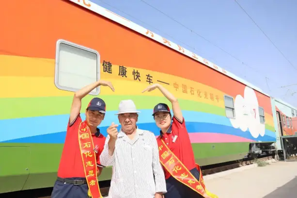 A patient poses for a picture with volunteers in front of the "Sinopec Lifeline Express" hospital train. (Photo from Sinopec)