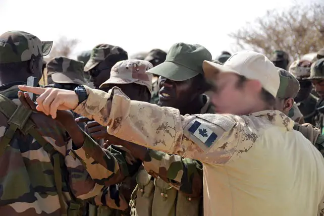 Un membre du Régiment d’opérations spéciales du Canada enseigne à un sergent comment utiliser correctement un inclinomètre pour déterminer la vitesse du vent, à Agadez, au Niger, le 21 février 2014. (Archives/Spc. Timothy Clegg/US Army)