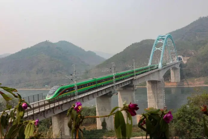 A train from Kunming, capital of southwest China's Yunnan province, to Vientiane, capital of Laos, passes over a bridge along the China-Laos Railway in Jinghong, Xishuangbanna Dai autonomous prefecture, Yunnan province. (Photo by Li Yunsheng/People's Daily Online)