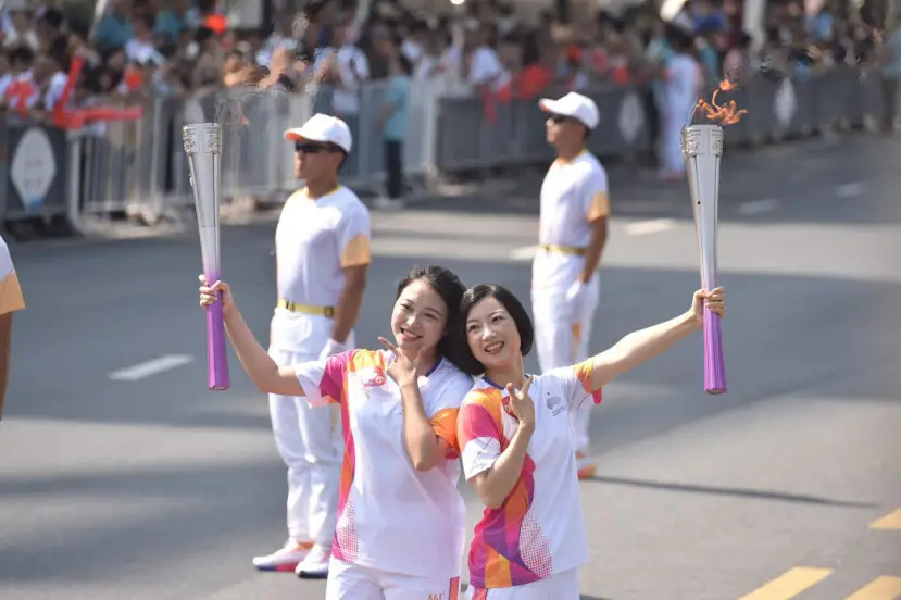 Wang Jie (right), the 45th torchbearer of the Hangzhou Asian Games from China Telecom Zhejiang Branch, passes the flame to Liu Han (left), the 46th torchbearer from Zhejiang Normal University, during a torch relay, Sept. 19, 2023. (Photo by Pan Haisong/People's Daily Online)
