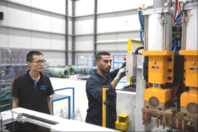 A Chinese technician instructs an Egyptian employee in a dishwasher factory of Midea (Egypt) Kitchen & Water Heater Appliances Co., Ltd. (Photo by Zhang Zhiwen/People's Daily)