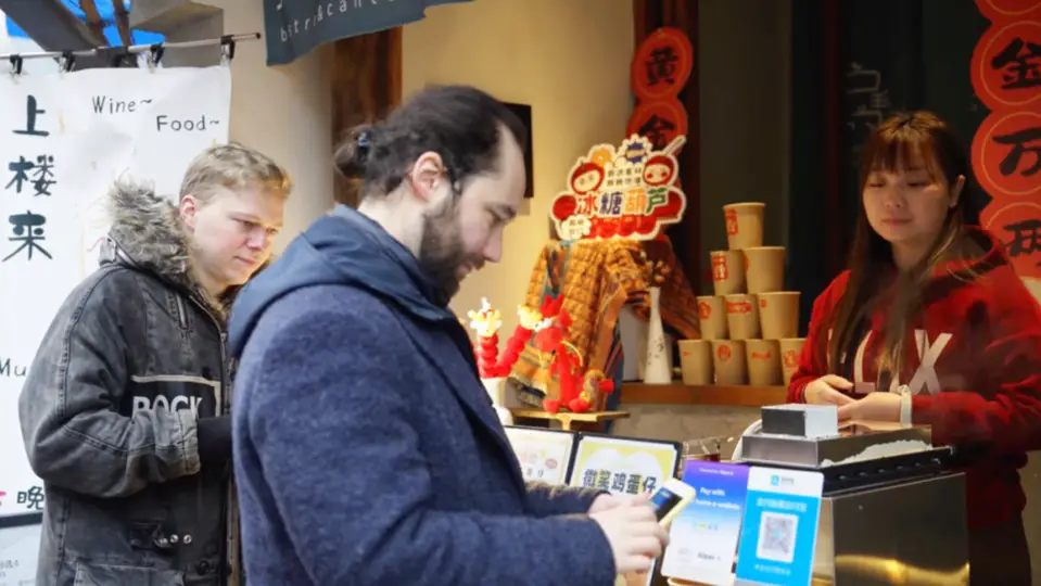 A foreign tourist scans a QR code to pay for snacks. (Photo from Alipay)