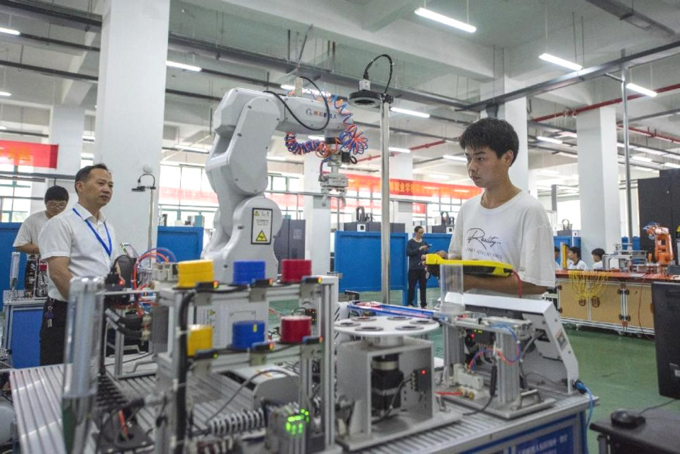Students at Wuhu Machine Engineering School, east China's Anhui province join an industrial robot operation competition. (Photo by Xiao Benxiang/People's Daily Online)