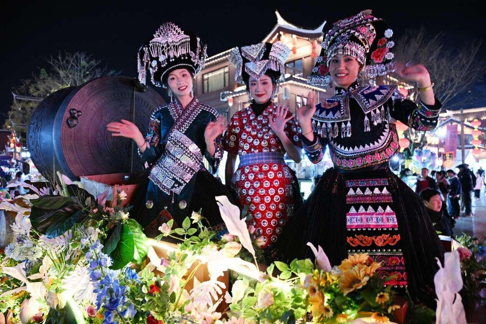 Performers strike a pose against a backdrop of an ancient town in Wenshan Zhuang and Miao autonomous prefecture, southwest China's Yunnan province, Jan. 30, 2025. (Photo by Xiong Pingxiang/People's Daily Online)