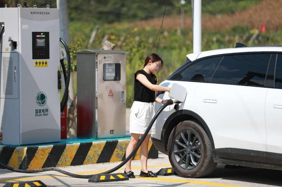A new energy vehicle (NEV) owner charges her car at a local station in Xiamadong village, Badong county, Enshi Tujia and Miao autonomous prefecture, central China's Hubei province. (Photo by Jiao Guobin/People's Daily Online)