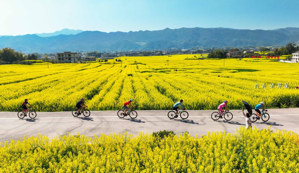 Cycling enthusiasts ride on a flower-surrounded road in Libai village, Dianjian county, southwest China's Chongqing municipality, March 25, 2025. (Photo by Gong Changhao/People's Daily Online)