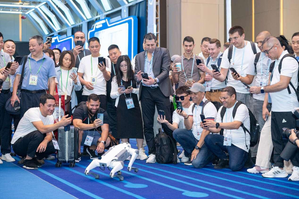Chinese and foreign visitors to the 137th session of the China Import and Export Fair, also known as the Canton Fair, take pictures of a robotic dog in an exhibition area for robots, Guangzhou, south China's Guangdong province, April 16, 2025. (Photo by Wu Wenjun/People's Daily Online)