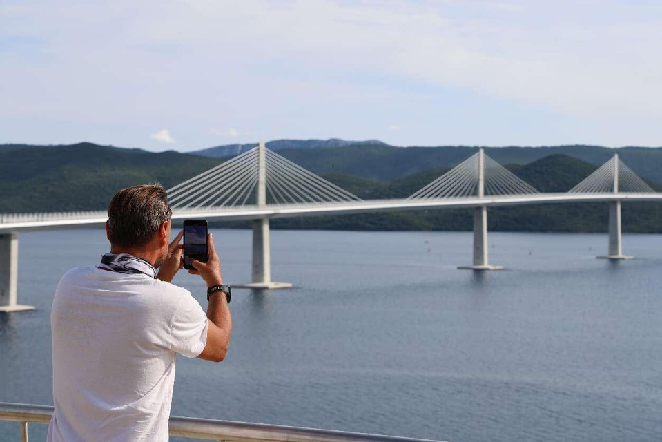 A local resident takes pictures of the Chinese-built Peljesac Bridge in Croatia. (Photo by Liu Zhonghua/People's Daily)