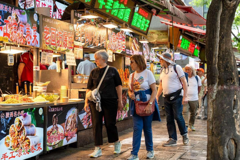 Foreign tourists visit a snack and commercial street in Lianhu district, Xi'an, northwest China's Shaanxi province, April 2, 2025. (Photo by Zhang Cheng/People's Daily Online)