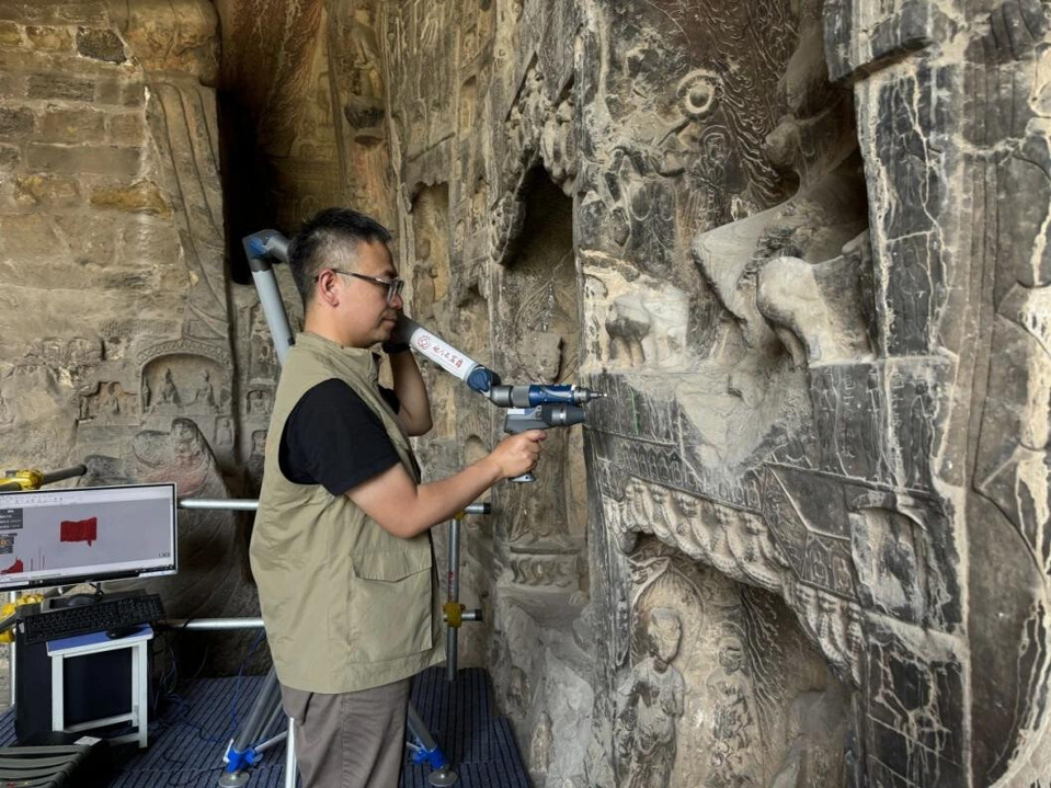 A researcher at the Longmen Grottoes Academy scans a cave of the Longmen Grottoes to collect digital data. (Photo by Zhang Wenhao/People's Daily)