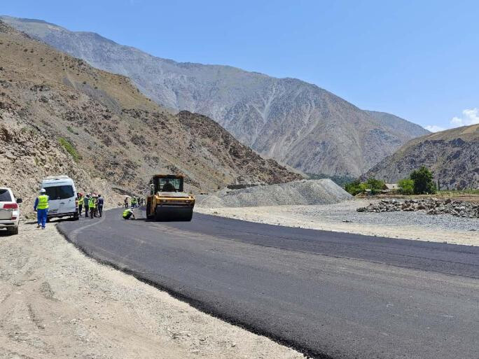 Chinese and Tajik workers pave an asphalt road as part of the second phase of the China-Tajikistan expressway. (Photo by Cheng Shijie/People's Daily)