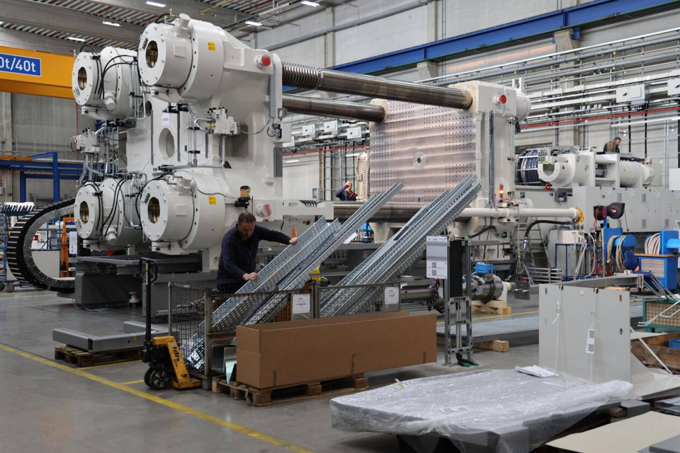 Technicians assemble and commission large injection molding equipment inside a workshop at KraussMaffei's new factory. (People's Daily/Liu Zhonghua)