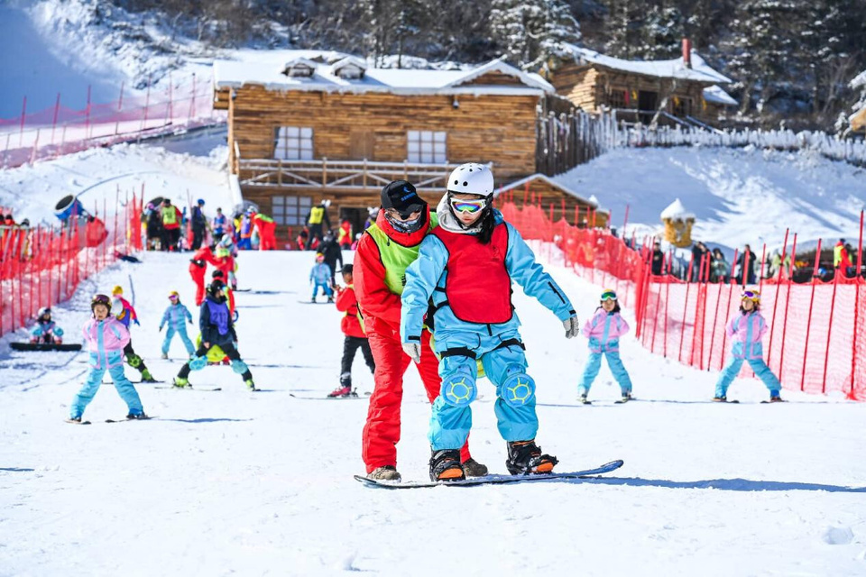 A coach teaches a tourist snowboarding at a ski resort in Yichun, east China's Jiangxi province. (Photo/Zhou Liang)